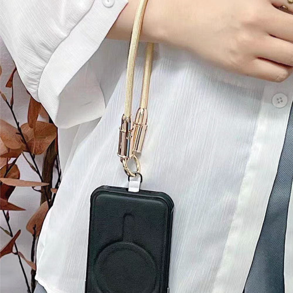 Una persona sostiene un teléfono con un cordón. El cordón es beige y el teléfono está en una funda negra.