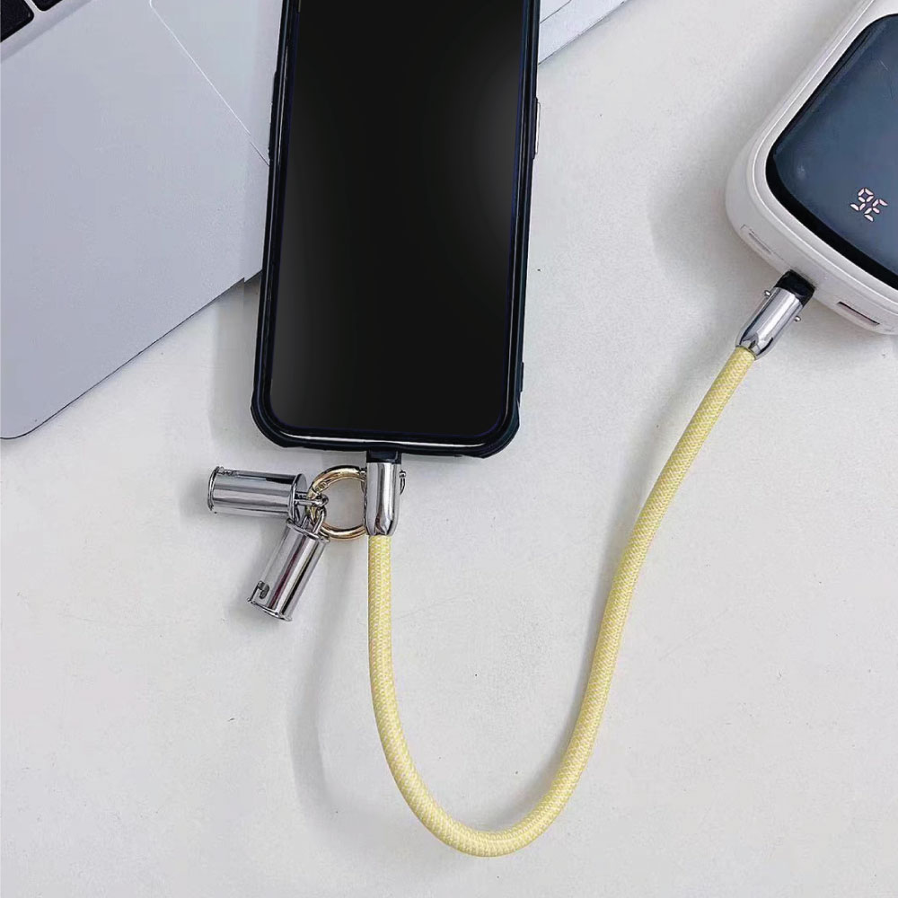 Un teléfono conectado a un banco de energía con un cable amarillo y conectores plateados.