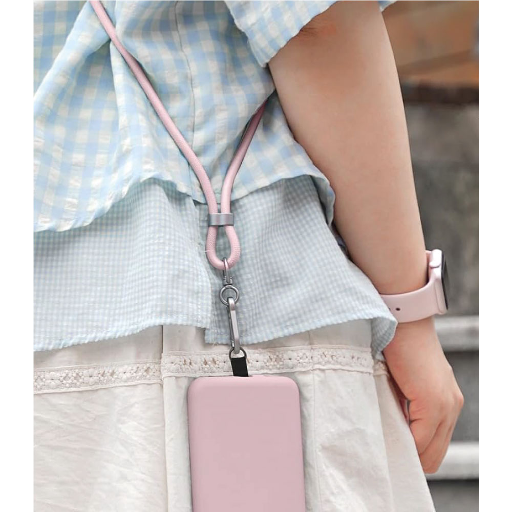 Mano de una persona sosteniendo un teléfono rosa con un cordón rosa.