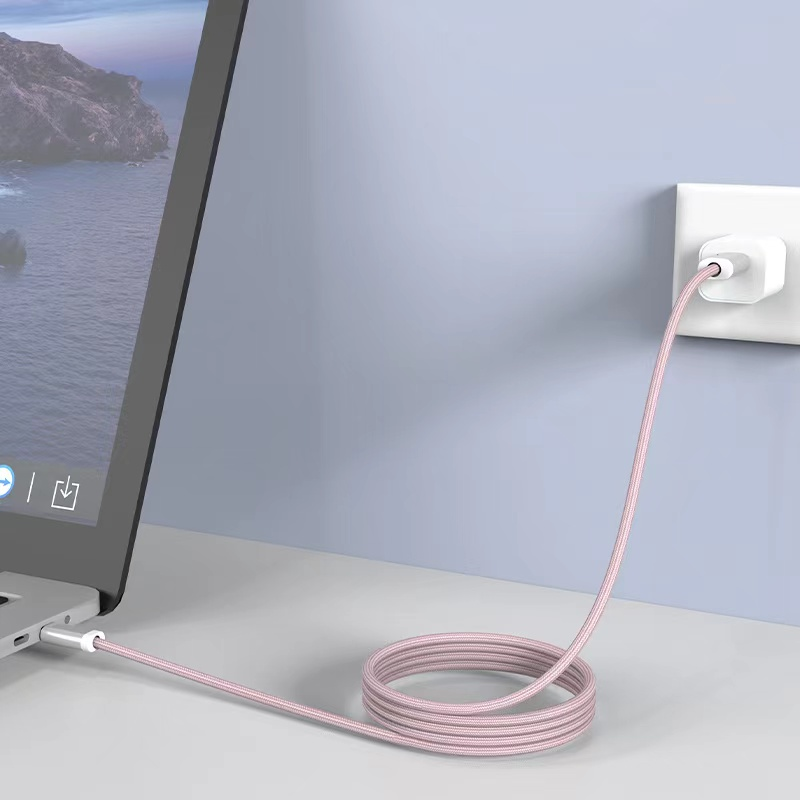 Portátil enchufado a una toma de corriente con un cable de carga rosa. El cable está enrollado.