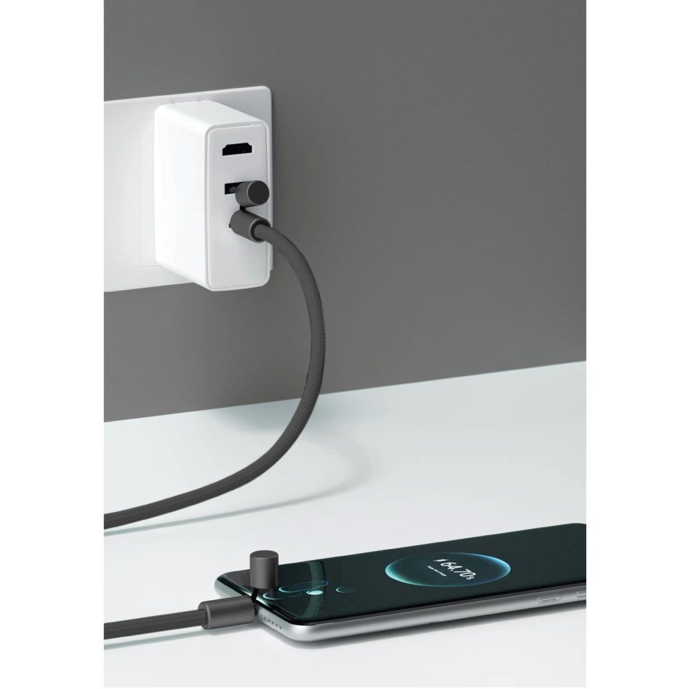 Un adaptador de corriente blanco enchufado a una toma de corriente, conectado a un teléfono por un cable gris oscuro.