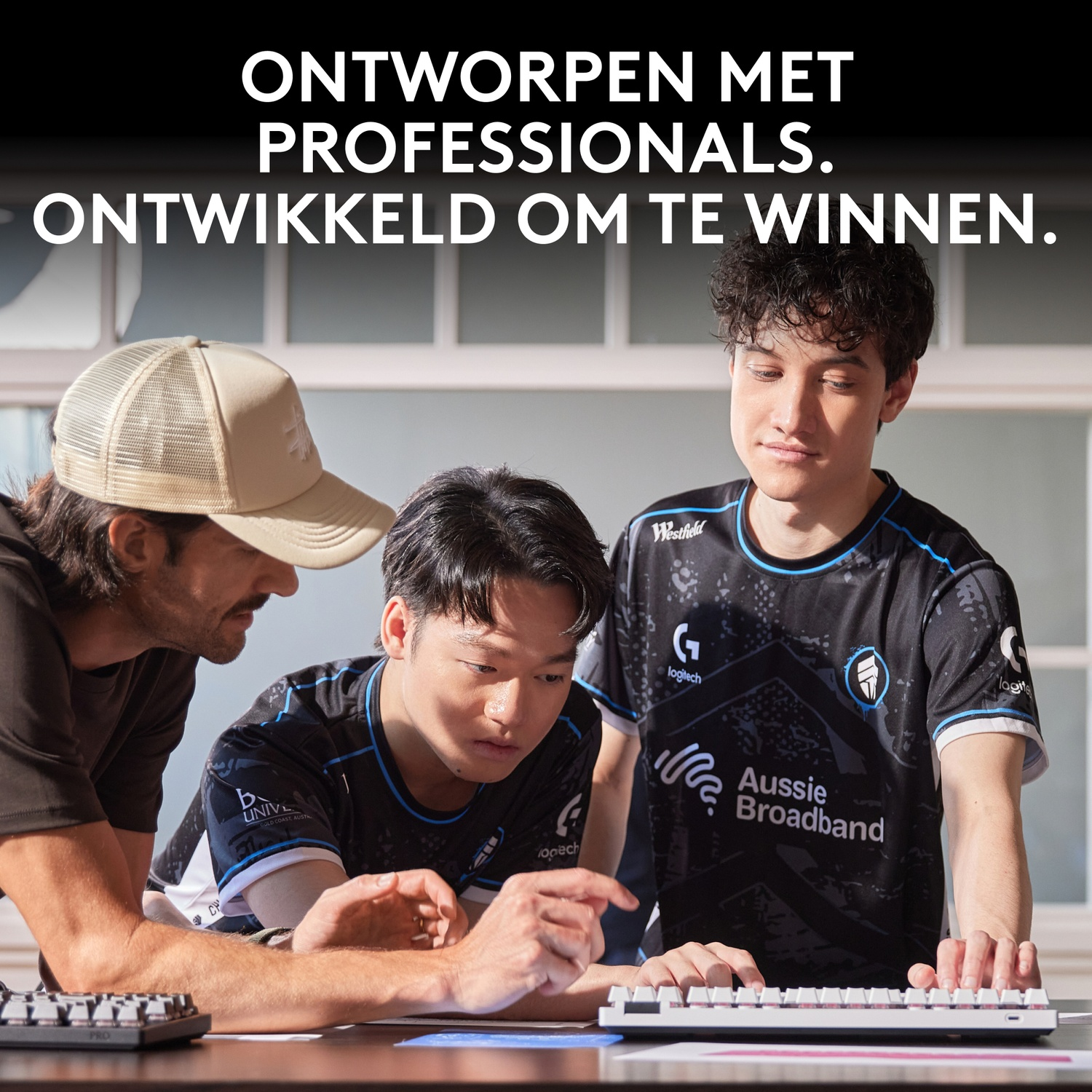 Three men in esports jerseys look at a keyboard.