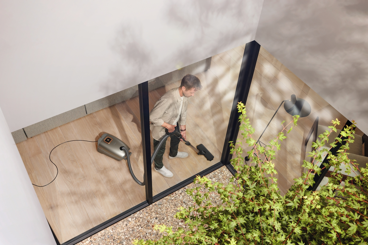 Ein Mann saugt einen Holzboden. Der Staubsauger ist gold und grau.