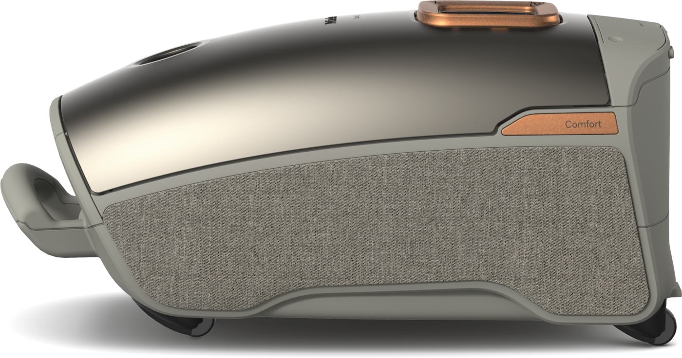 Ein moderner, silber-grauer Staubsauger. Er hat eine Stoffblende, kupferfarbene Akzente und das Wort 'Comfort' an der Seite.