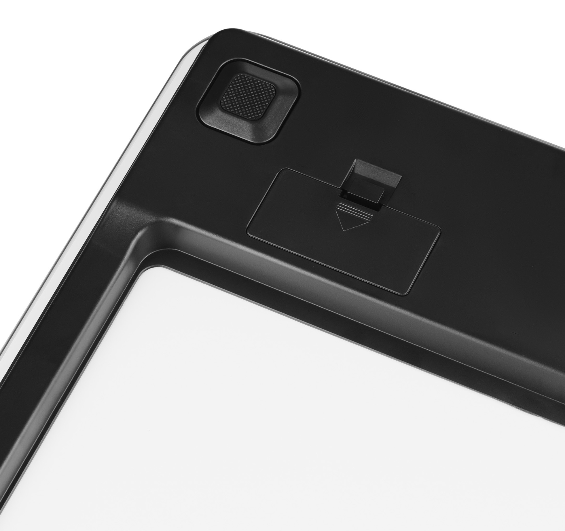 Czarne urządzenie z przyciskiem i gniazdem na baterię. Białe tło.