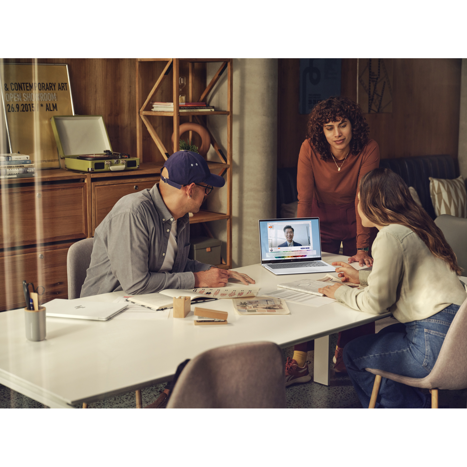 Trois personnes dans un cadre de bureau, en visioconférence sur un ordinateur portable.