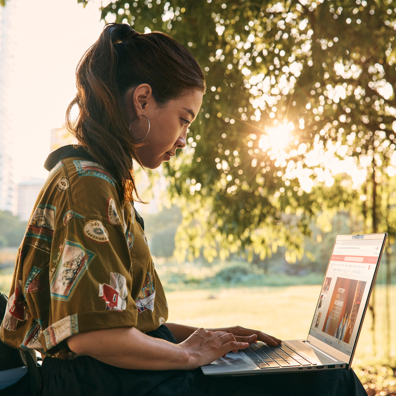 Vrouw die laptop gebruikt in park, zon schijnt.