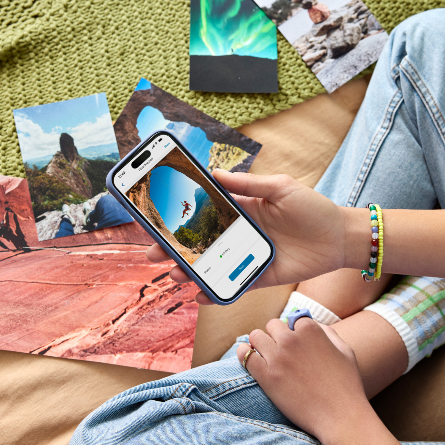 Person holding phone showing photo, with other photos and accessories around.