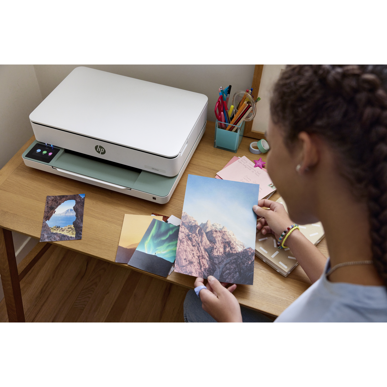 Personne regardant des photos imprimées par une imprimante blanche sur un bureau.