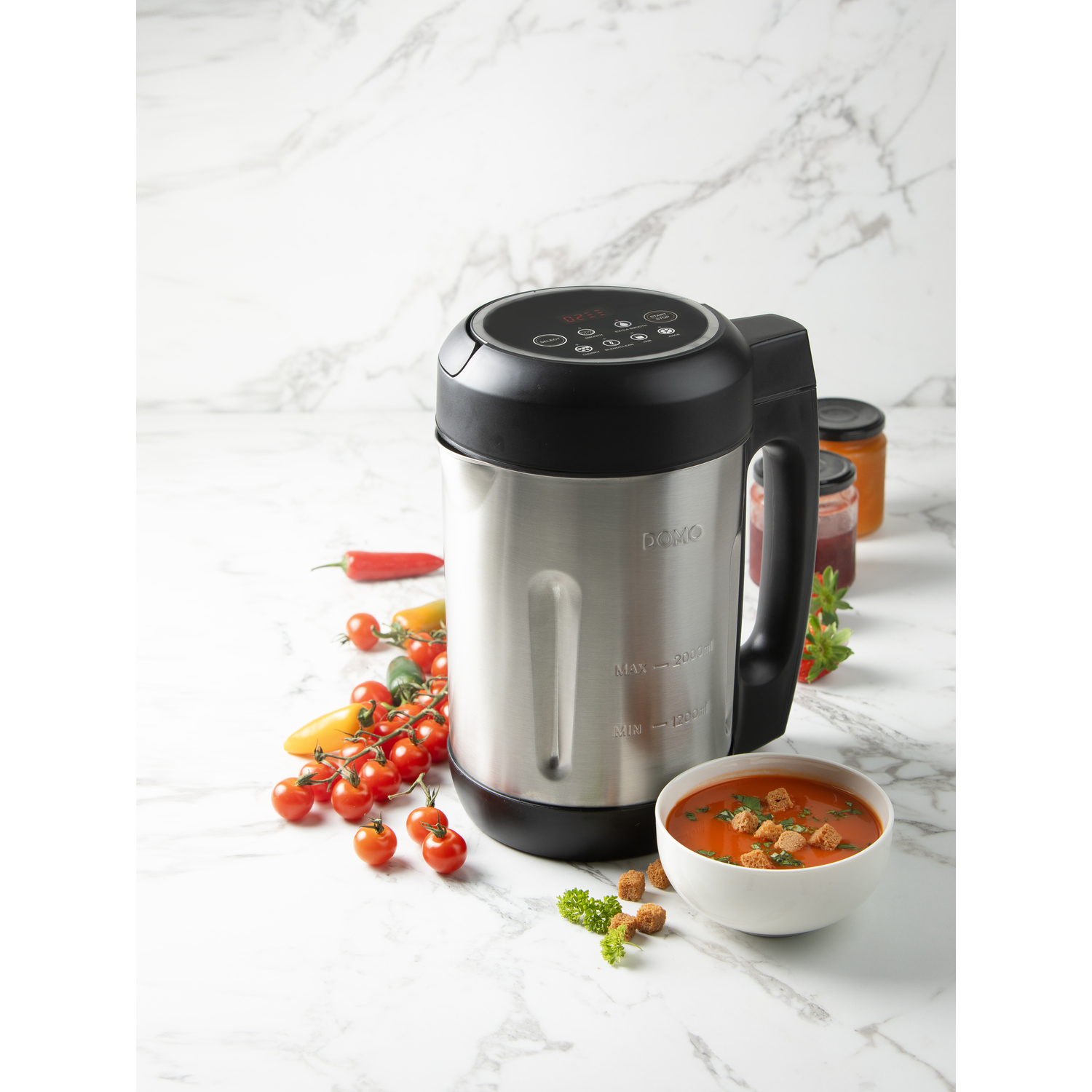 A stainless steel soup maker with a bowl of soup, tomatoes, and croutons.