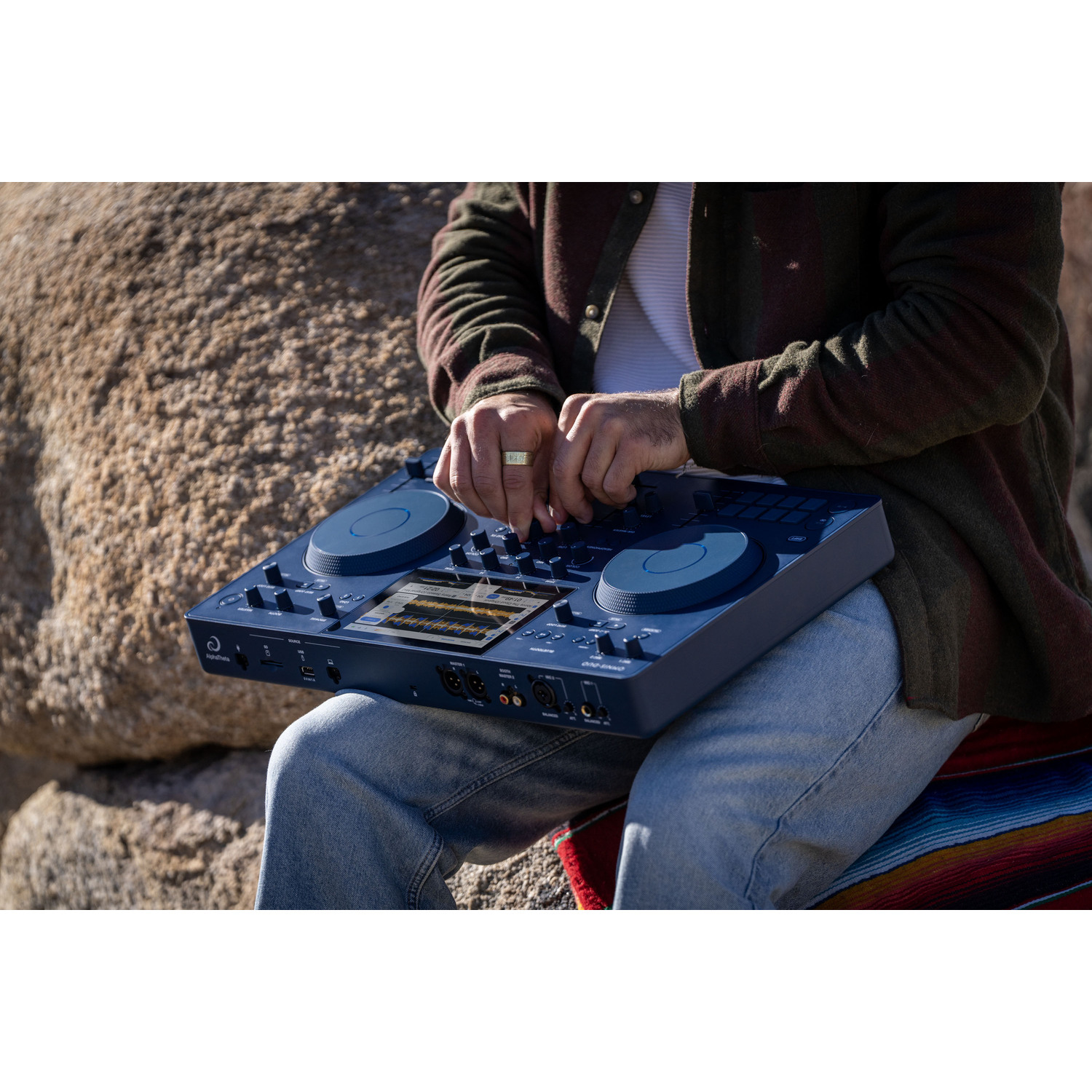Een DJ die op een blauwe console mixt in de buitenlucht.