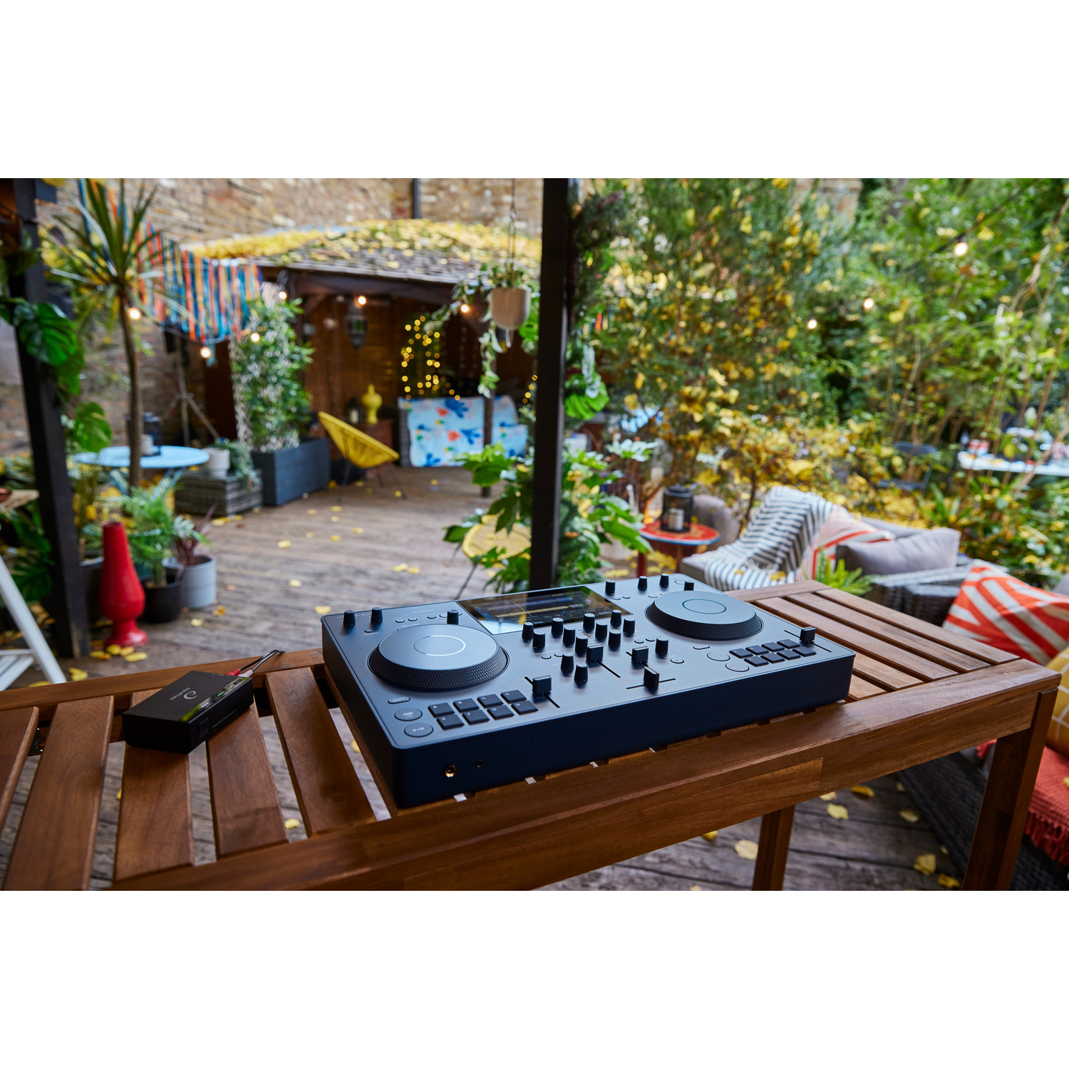 DJ-mixer op een houten tafel in een tuin. Inclusief een doos kaarten. Achtergrond: buitentuin.