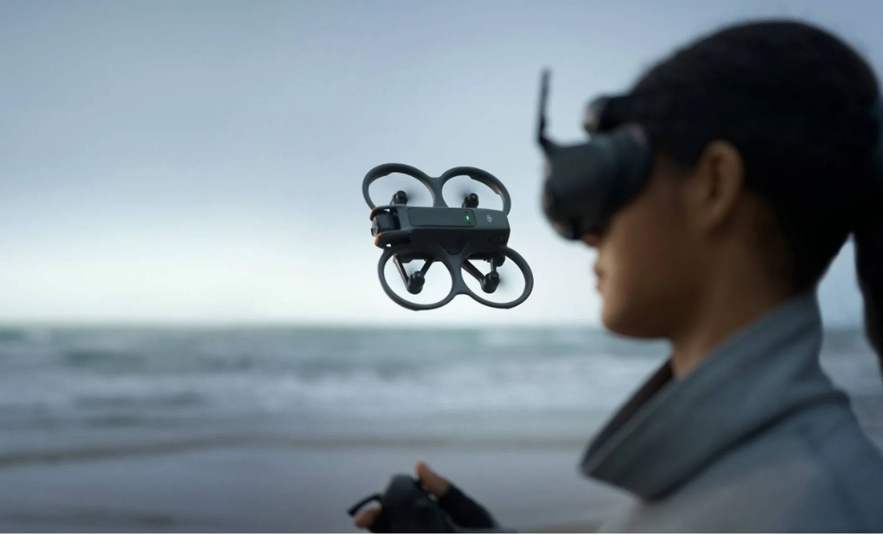 Osoba w goglach VR kontroluje drona nad plażą.