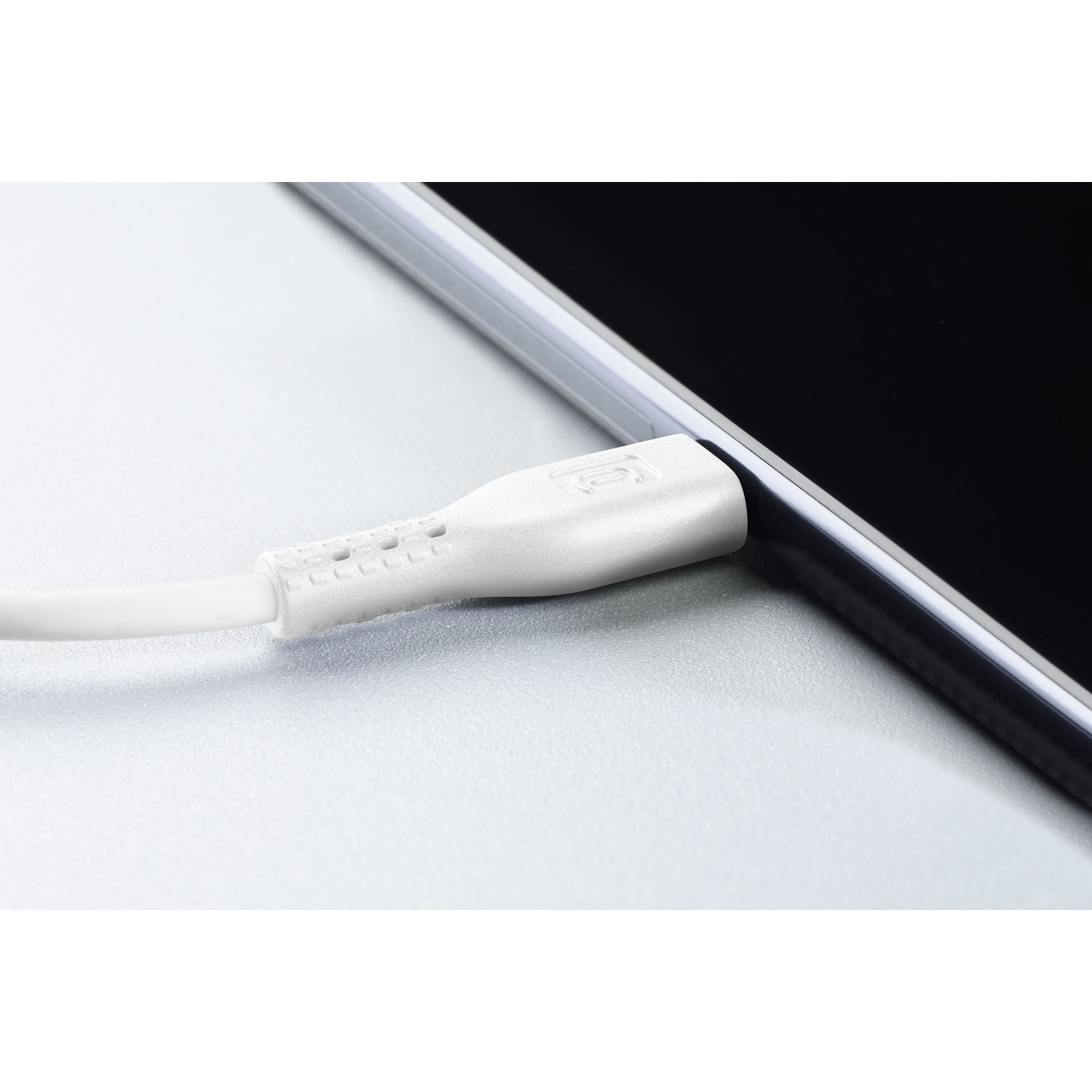 Cavo di ricarica bianco collegato a un tablet. Primo piano su una superficie grigio chiaro.