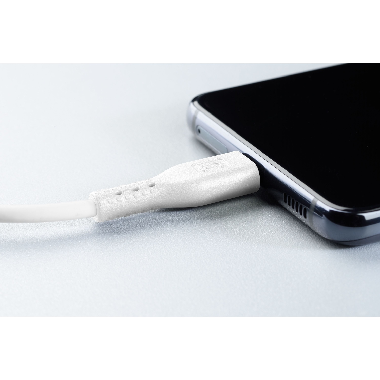 Cavo di ricarica bianco collegato a uno smartphone nero. Lo sfondo è grigio.