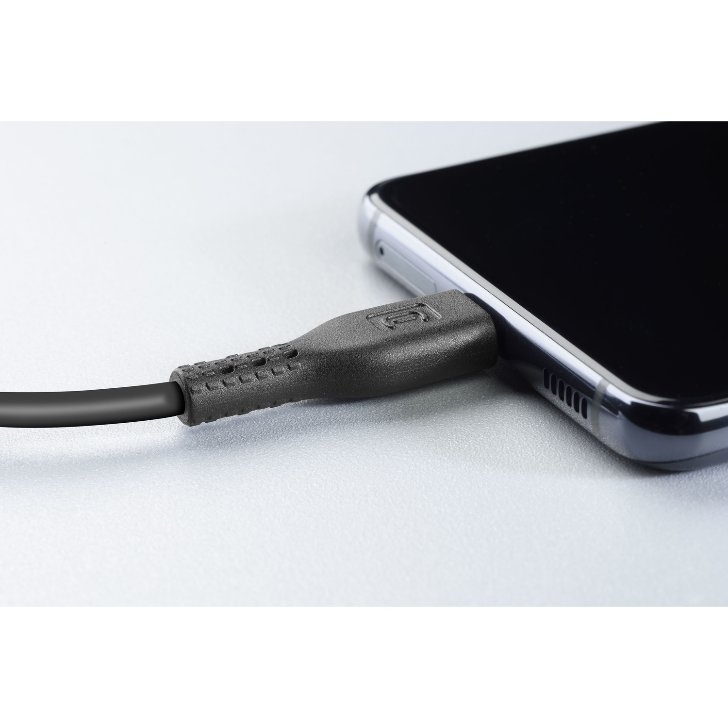Primo piano di un cavo di ricarica nero collegato a uno smartphone nero.
