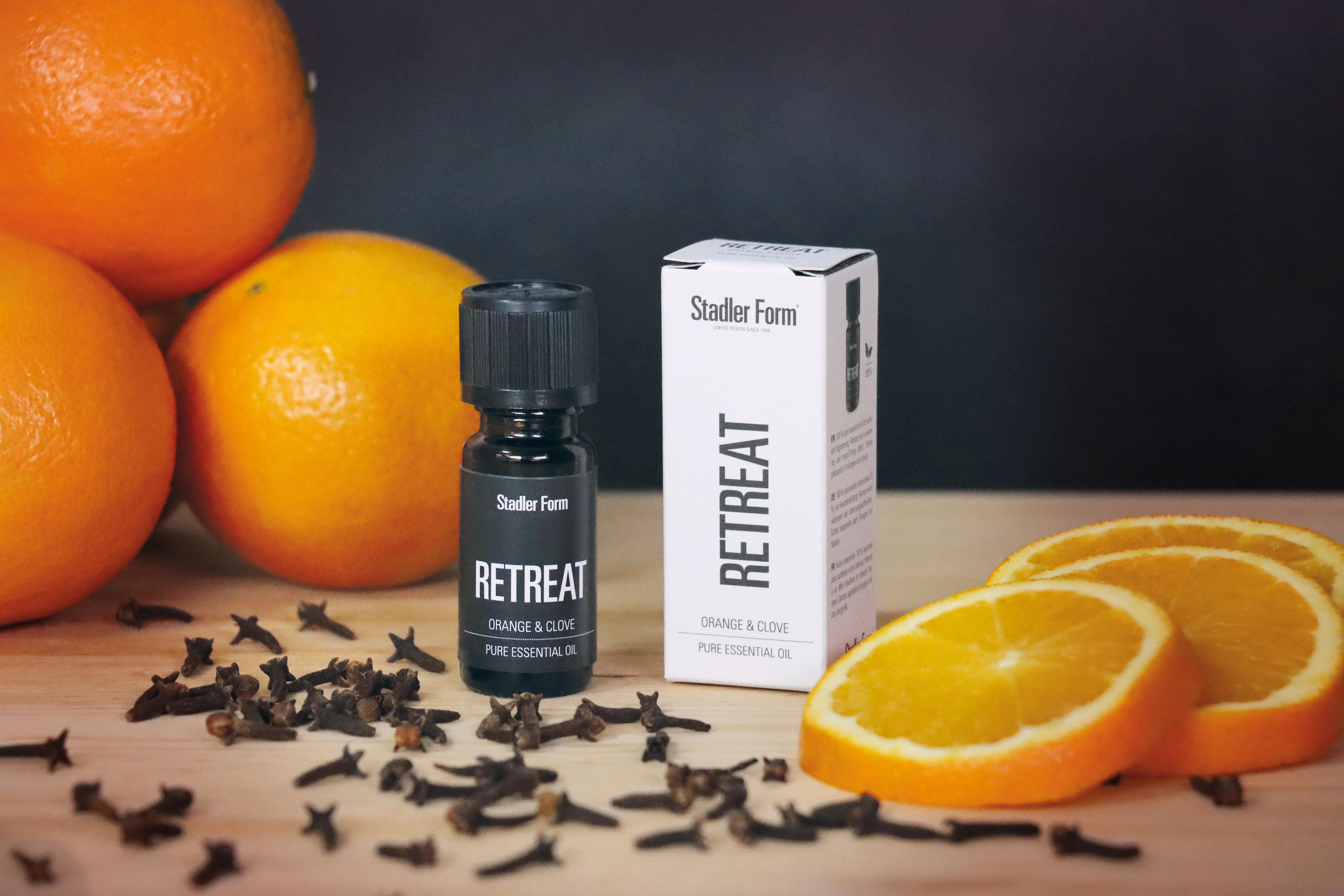 Ätherische Ölflasche, Orangenscheiben, Gewürznelken, Holzoberfläche.