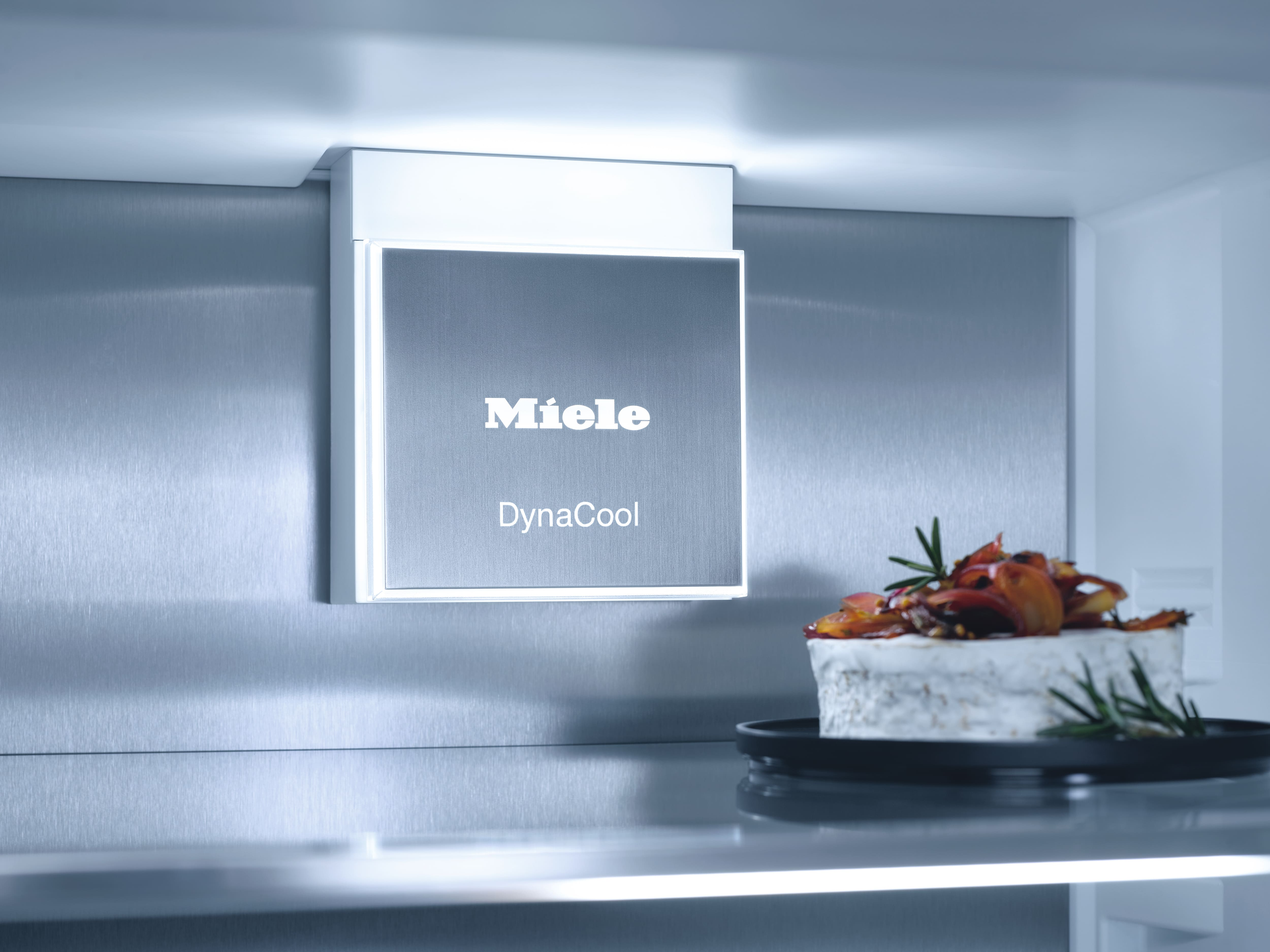 Miele DynaCool Kühlschrank-Innenraum. Enthält Regale, Lebensmittel und ein beleuchtetes DynaCool-Schild.