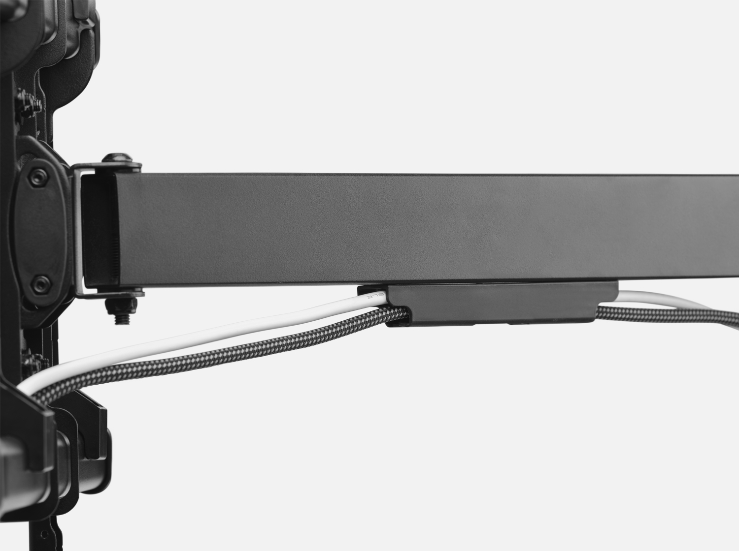 Gros plan sur un support TV noir avec des câbles. Les fils sont bien rangés.