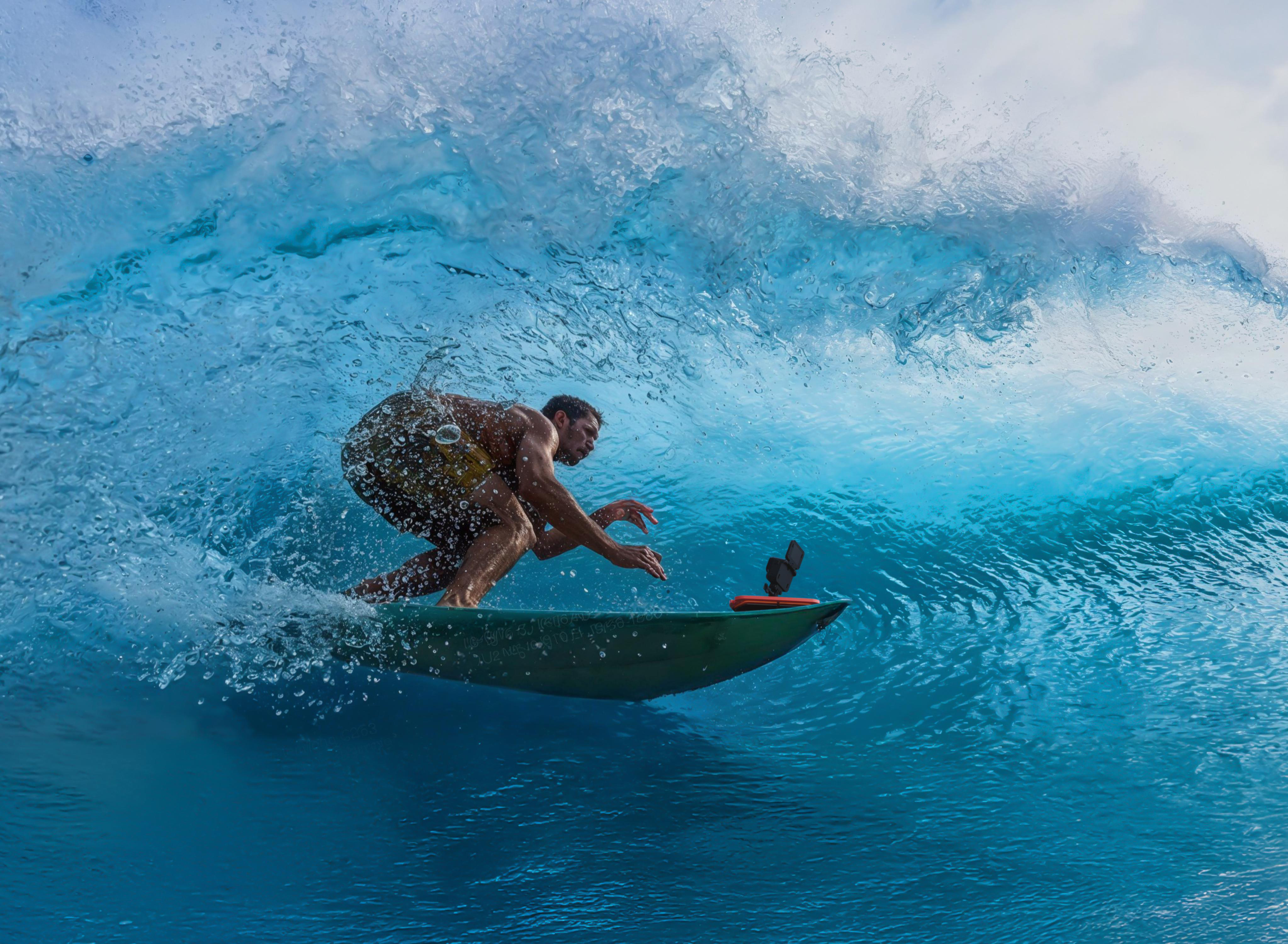 Surfer auf grünem Board in einer großen blauen Welle mit Spritzern.