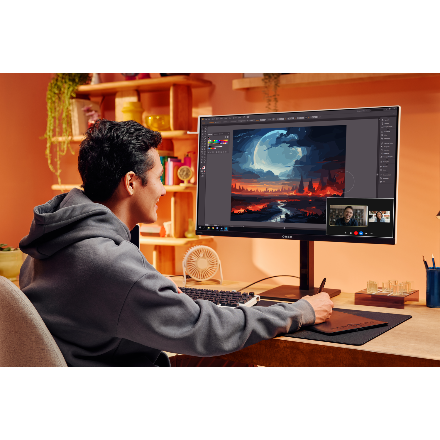 A person using a monitor with a graphic design on screen, and a video call window.