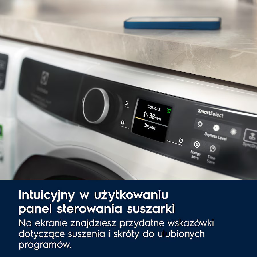 Zbliżenie białego panelu sterowania pralki, wyświetlającego ustawienia suszenia i czas. Niebieski telefon na górze.