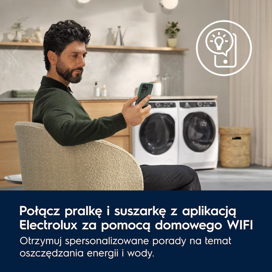 Mężczyzna siedzi używając smartfona. W tle pralka i suszarka.