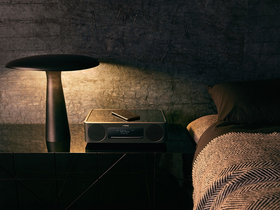 Scena sypialni z lampą, głośnikiem i łóżkiem.