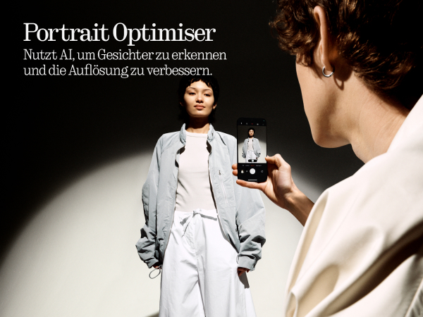 Zwei Personen, eine macht ein Foto einer Frau mit einem Telefon.