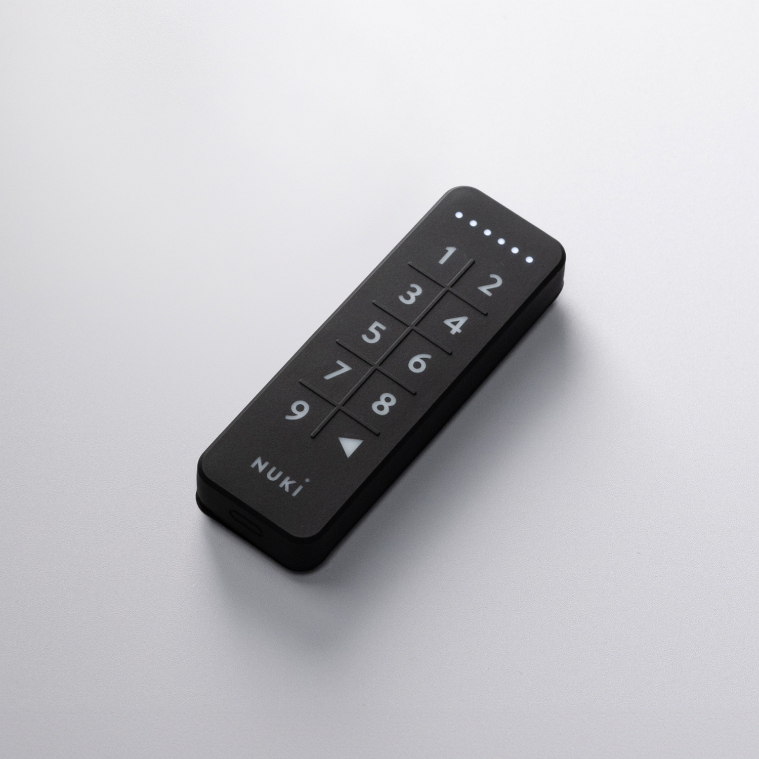 Teclado Nuki negro con números y botones táctiles sobre una superficie blanca.