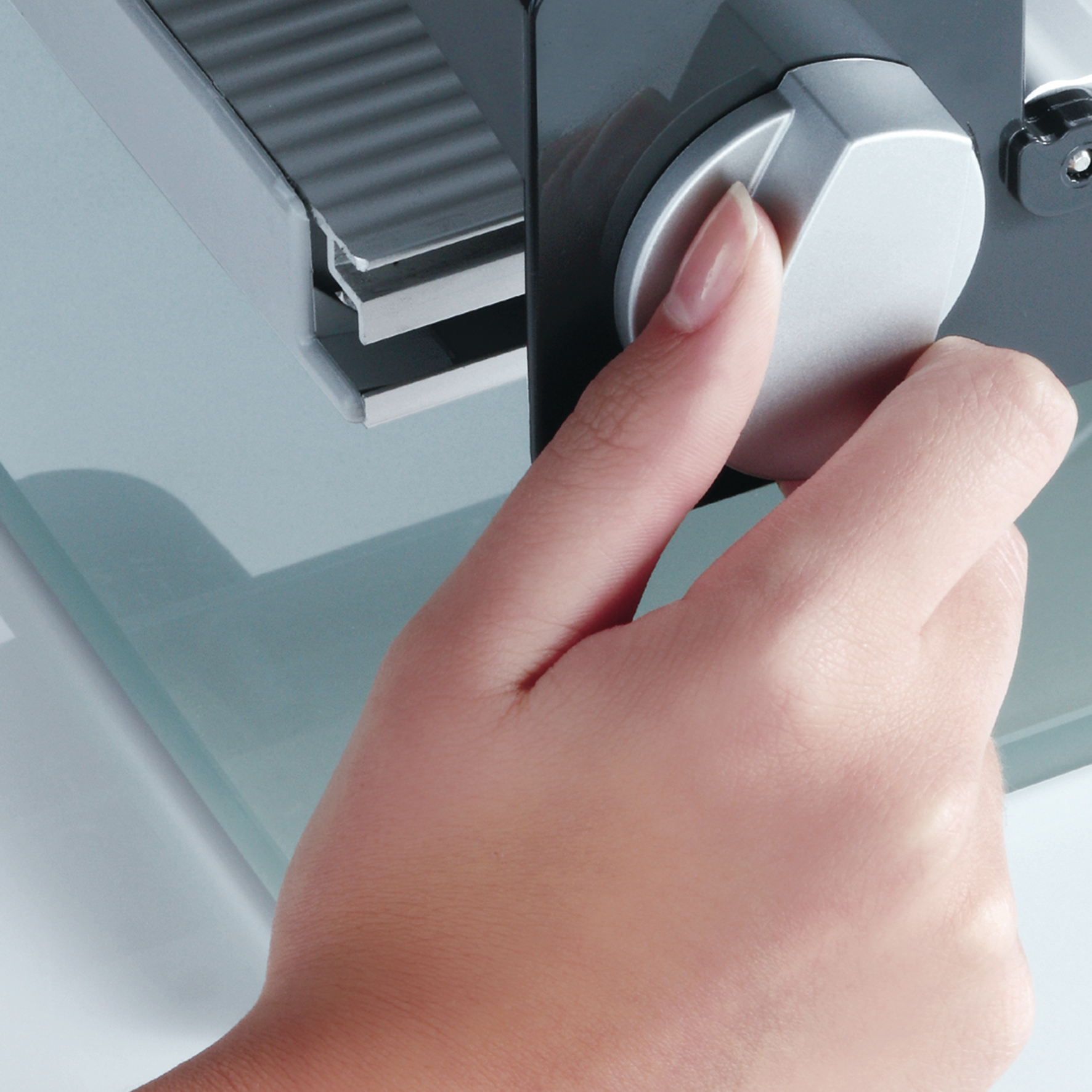 Eine Hand dreht einen Drehknopf an einem grau-weißen Gerät. Fokus auf Hand und Drehknopf.