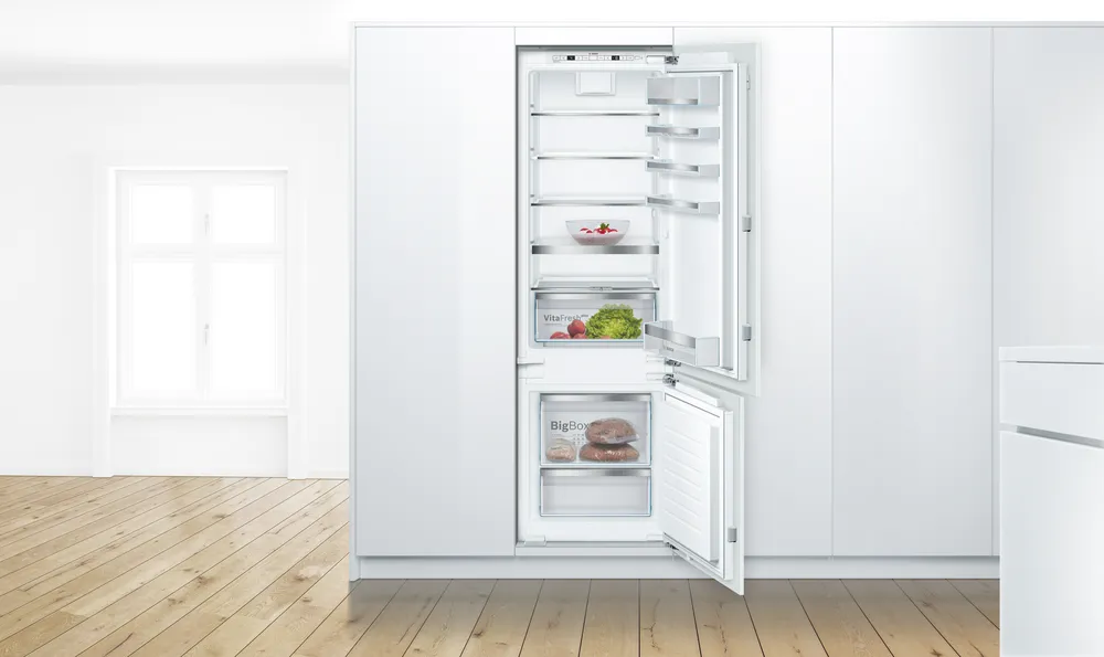 Weißer Einbaukühlschrank mit geöffneten Türen in einer Küche.