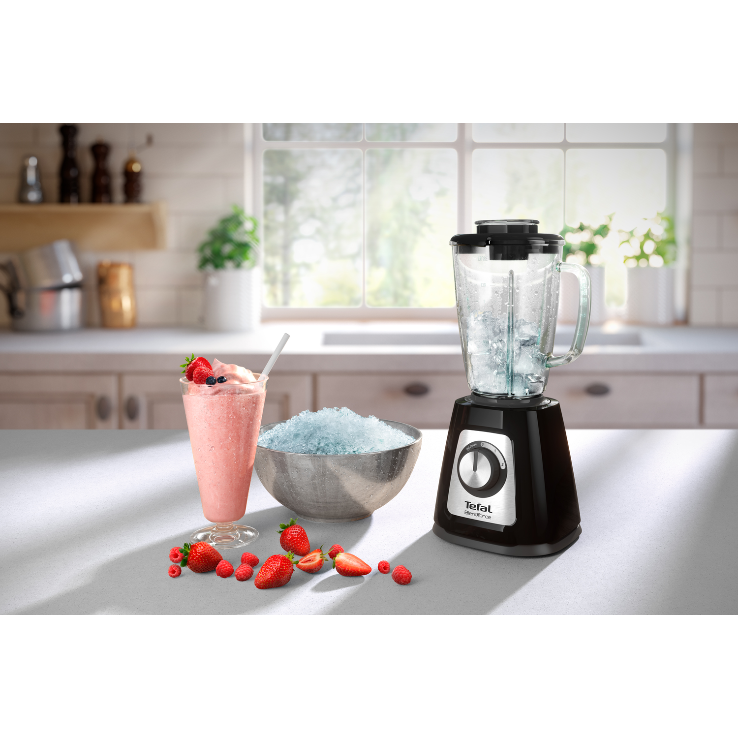 Blender met ijs, aardbeien en een smoothie in een glas.