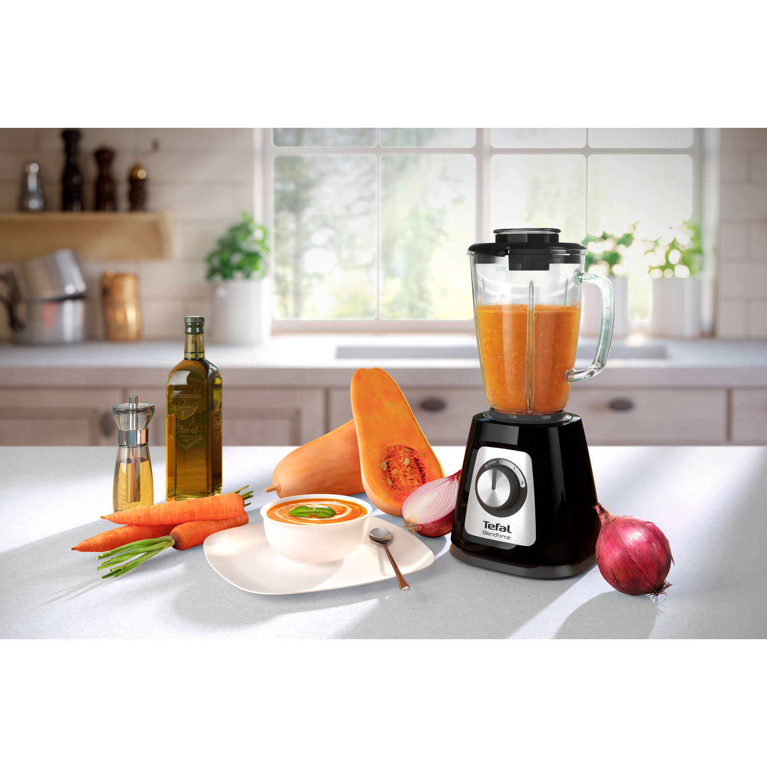 Blender met soep, wortelen, olie, pompoen, ui en wortelen. Een kom soep vooraan.