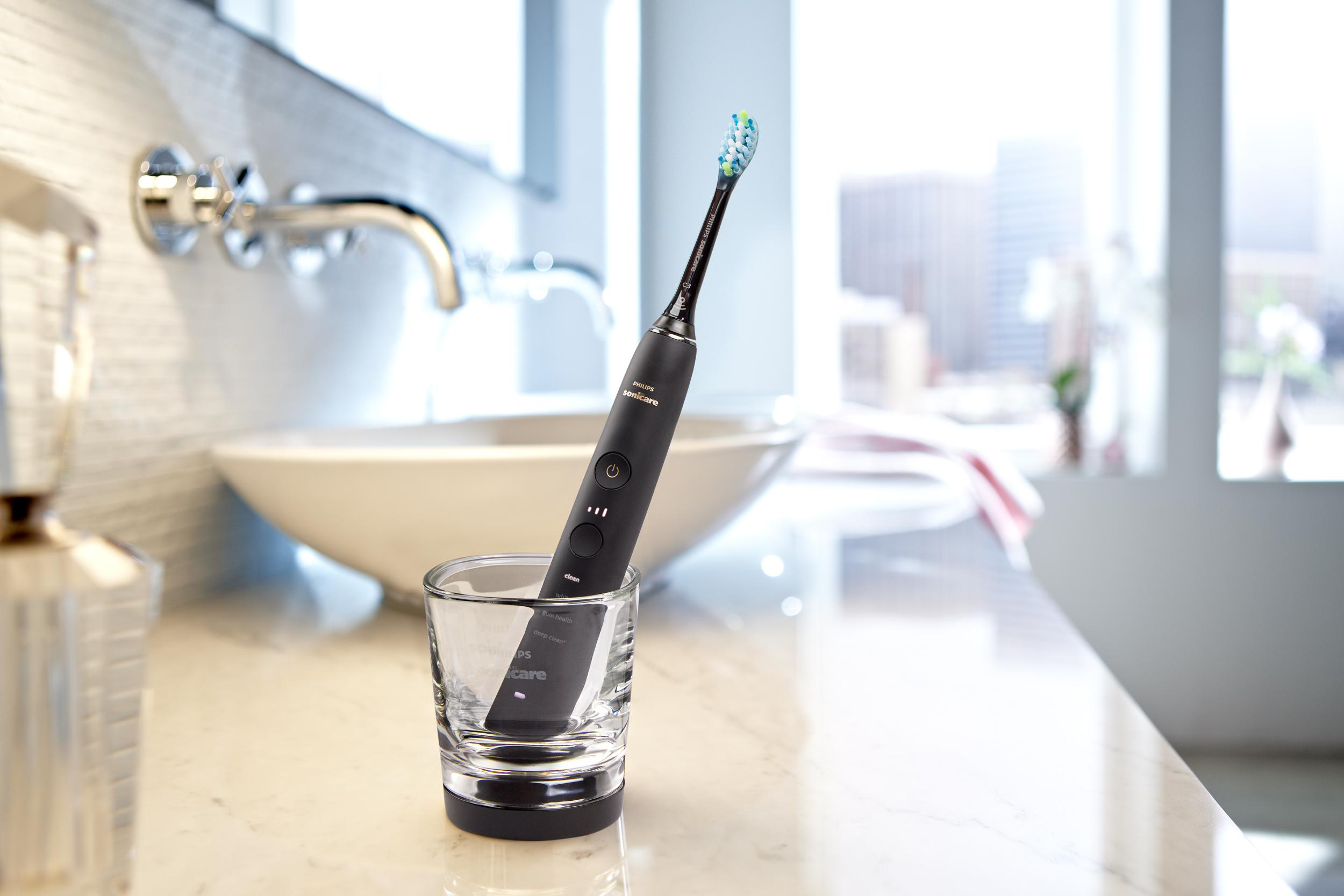 Schwarze elektrische Zahnbürste in einem Glas, auf Marmor.