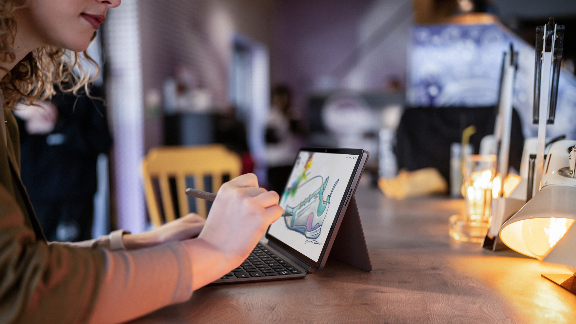 Frau, die ein Tablet mit Stift auf einer Holzbar benutzt. Eine Caféeinstellung mit Lichtern.