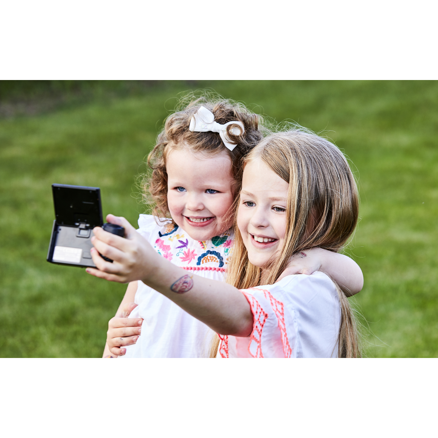 Deux jeunes filles prennent un selfie avec un téléphone portable en plein air.