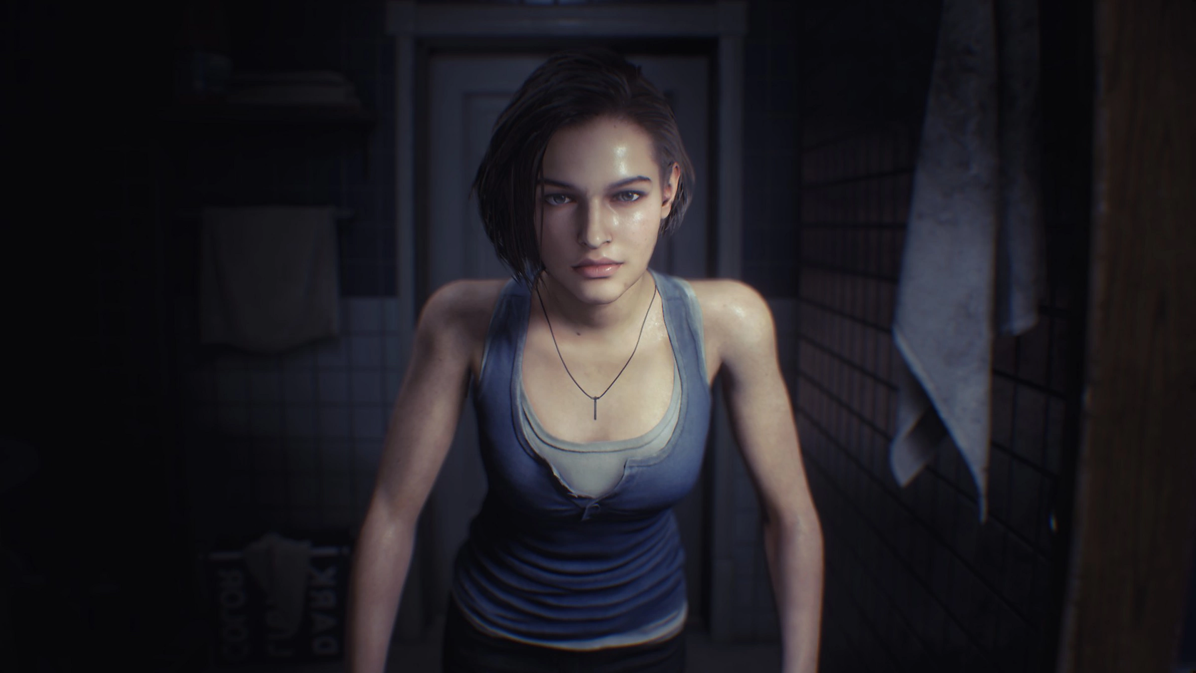 Eine Frau mit kurzen Haaren in einem Tanktop, die in einem dunklen Raum steht. Das Bild stammt aus einem Videospiel.