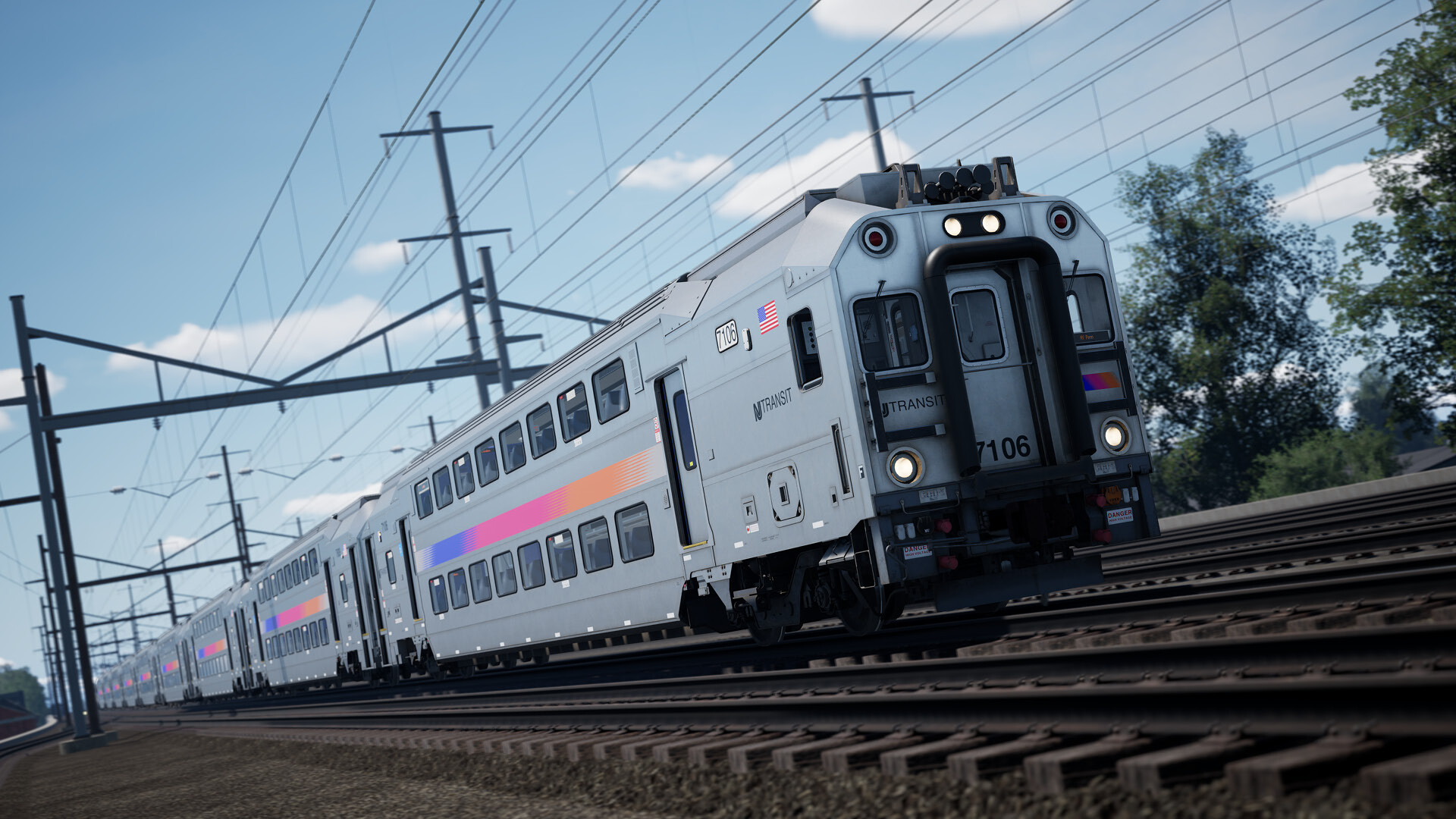 Un treno in movimento sui binari. Il treno ha il logo NJ Transit. Il cielo è blu con nuvole. Alberi ai lati.
