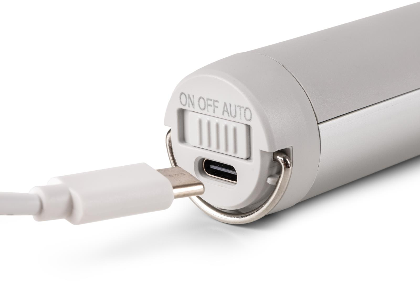 Egy töltőcsatlakozó közeli képe csatlakoztatott fehér kábellel, be/ki kapcsolóval és USB-C-vel.