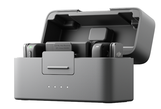 Szare etui ładujące z dwoma mikrofonami i odbiornikiem w środku, na białym tle.