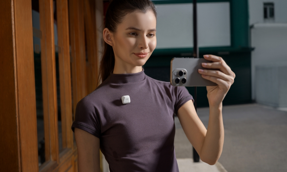 Kobieta trzyma telefon robiąc selfie. Kwadratowe urządzenie na koszuli.