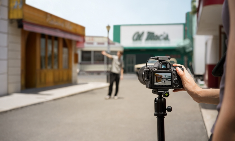 Osoba trzymająca aparat, robiąca zdjęcie osobie na planie ulicznym.