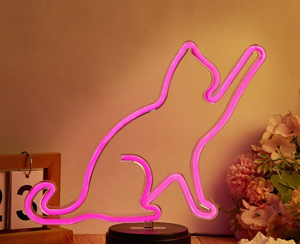 Neonowa sylwetka kota. Różowe światło. Kot sięga w górę. Ciemne tło.