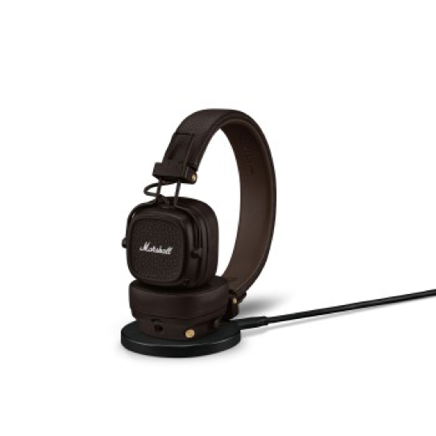 Brown Marshall headphones on a black charging base with a black cable attached.