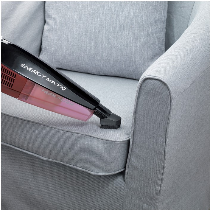 Odkurzacz czyszczący szarą sofę.