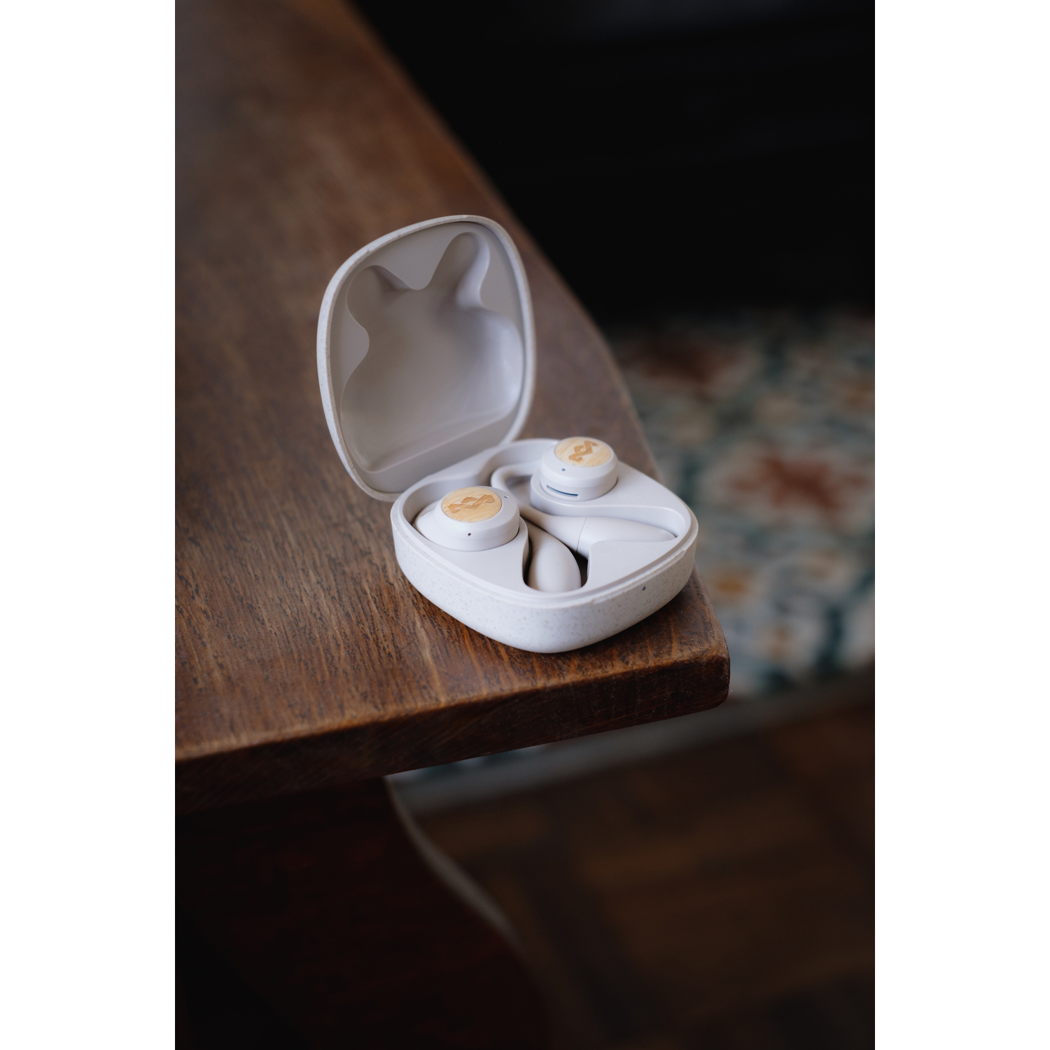 Écouteurs dans un étui blanc sur une table en bois. L'étui est ouvert, révélant les écouteurs.