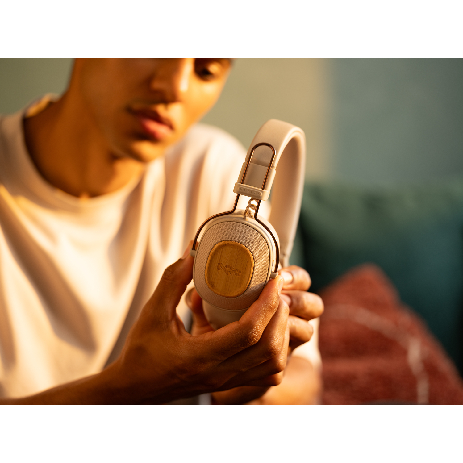 Une personne tient un casque Marshall beige. La personne porte une chemise blanche et est à l'intérieur.