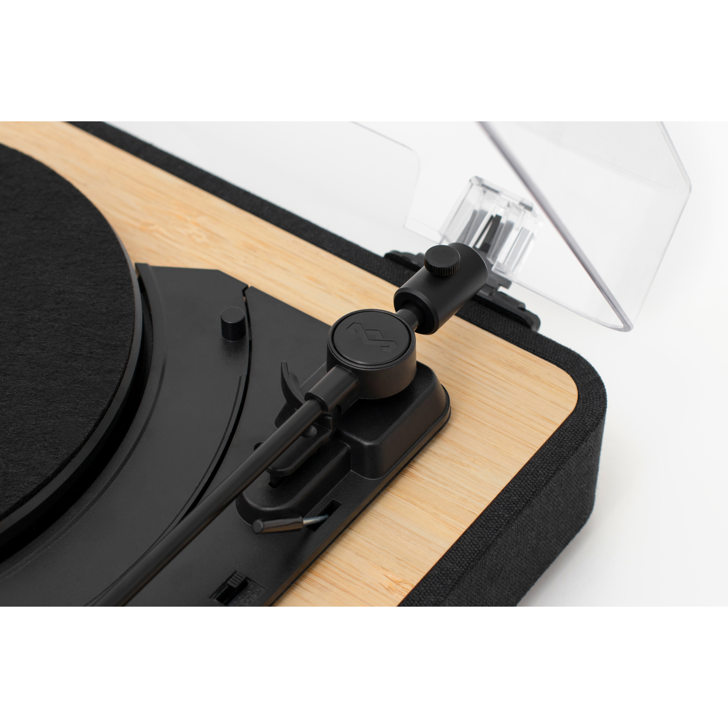 Close-up of a turntable with a black tonearm, a clear cover, and a wooden surface.