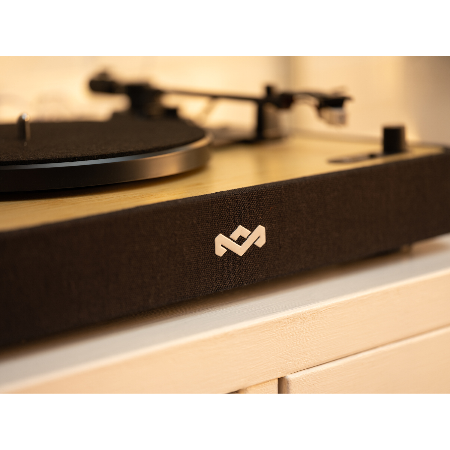 Turntable with a black record, a silver logo, and wooden accents on a white surface.